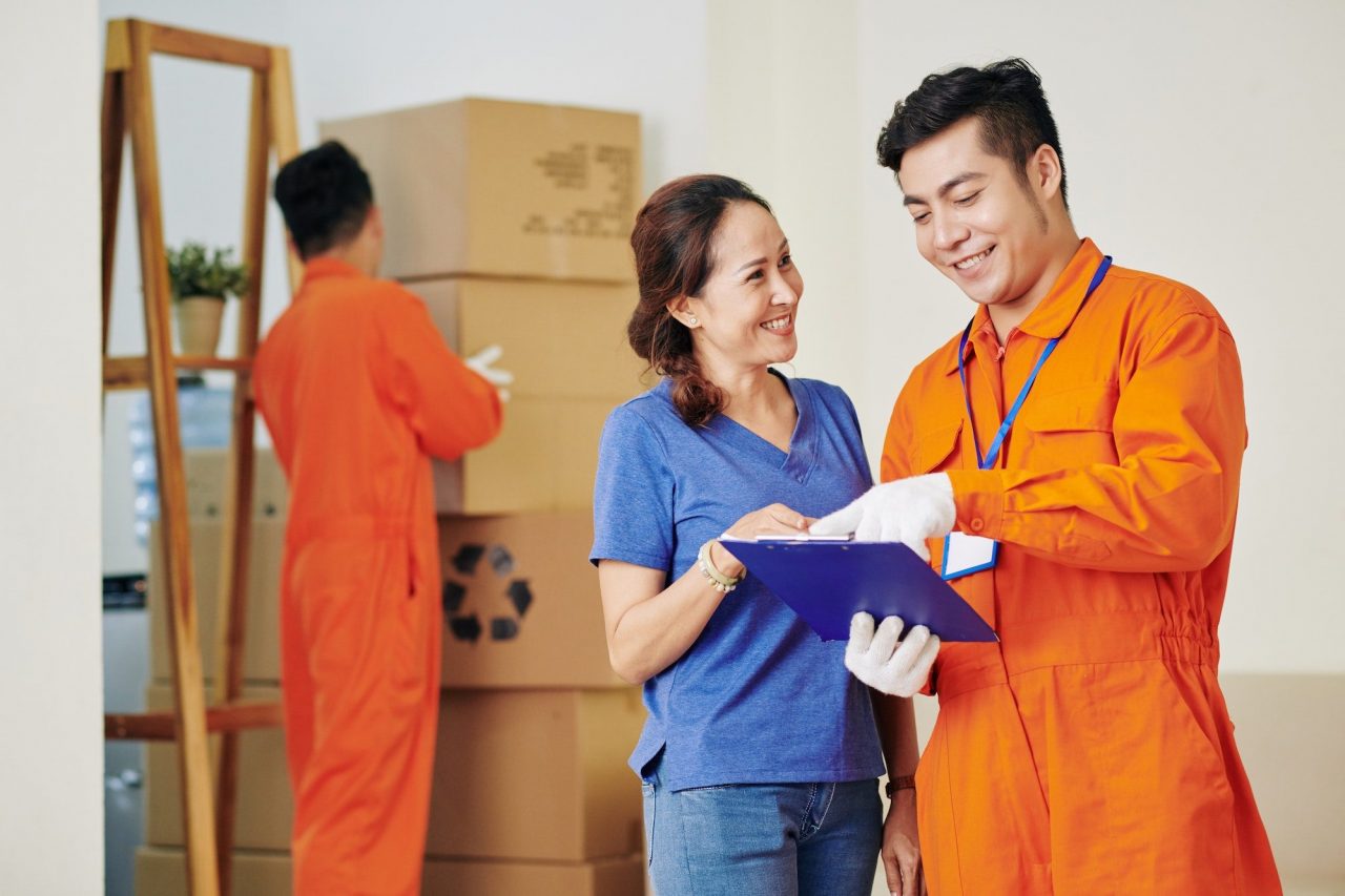 A man and woman in orange uniform standing next to boxes.