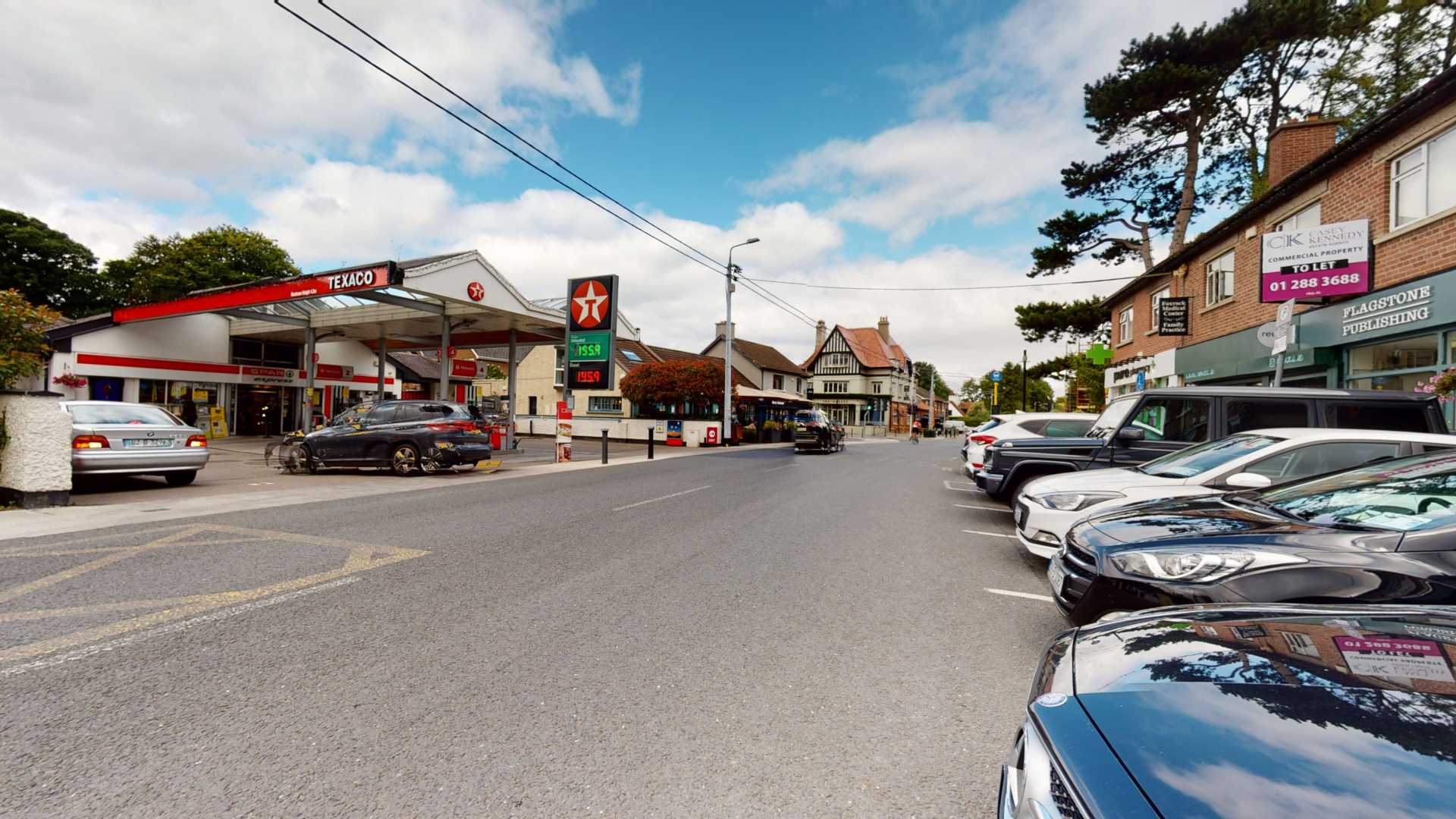 A street with cars parked in front of a gas station offering Expert Removals services.