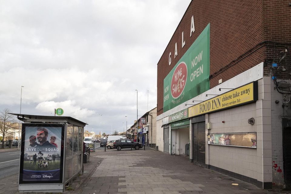 The corner of a street with a building, a bus stop, and an Expert Removals sign.