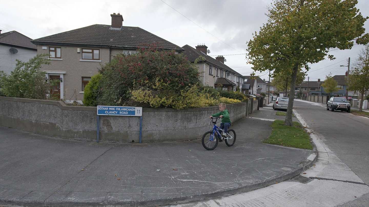 A boy riding a bike while passing by a street corner.