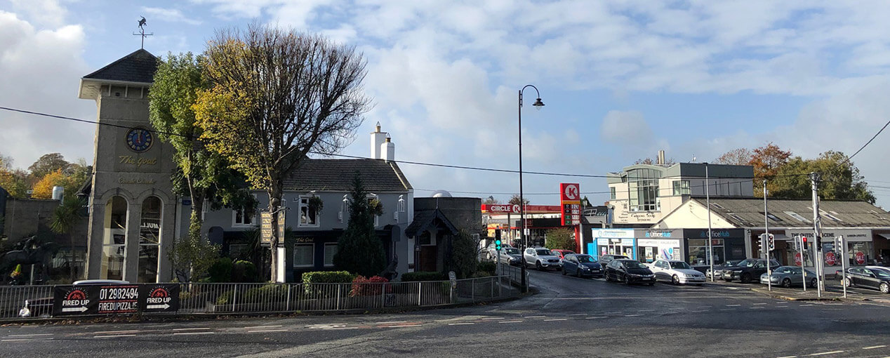 A street with parked cars and a clock tower, featuring Expert Removals.