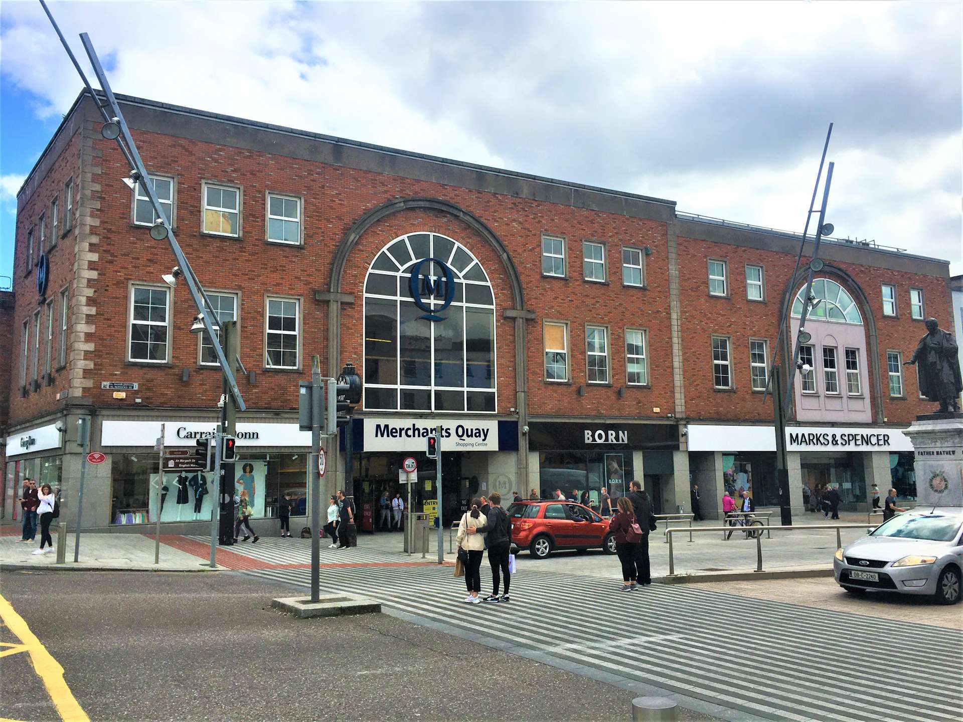 A vibrant street scene showcasing people walking in front of a prominently placed building.