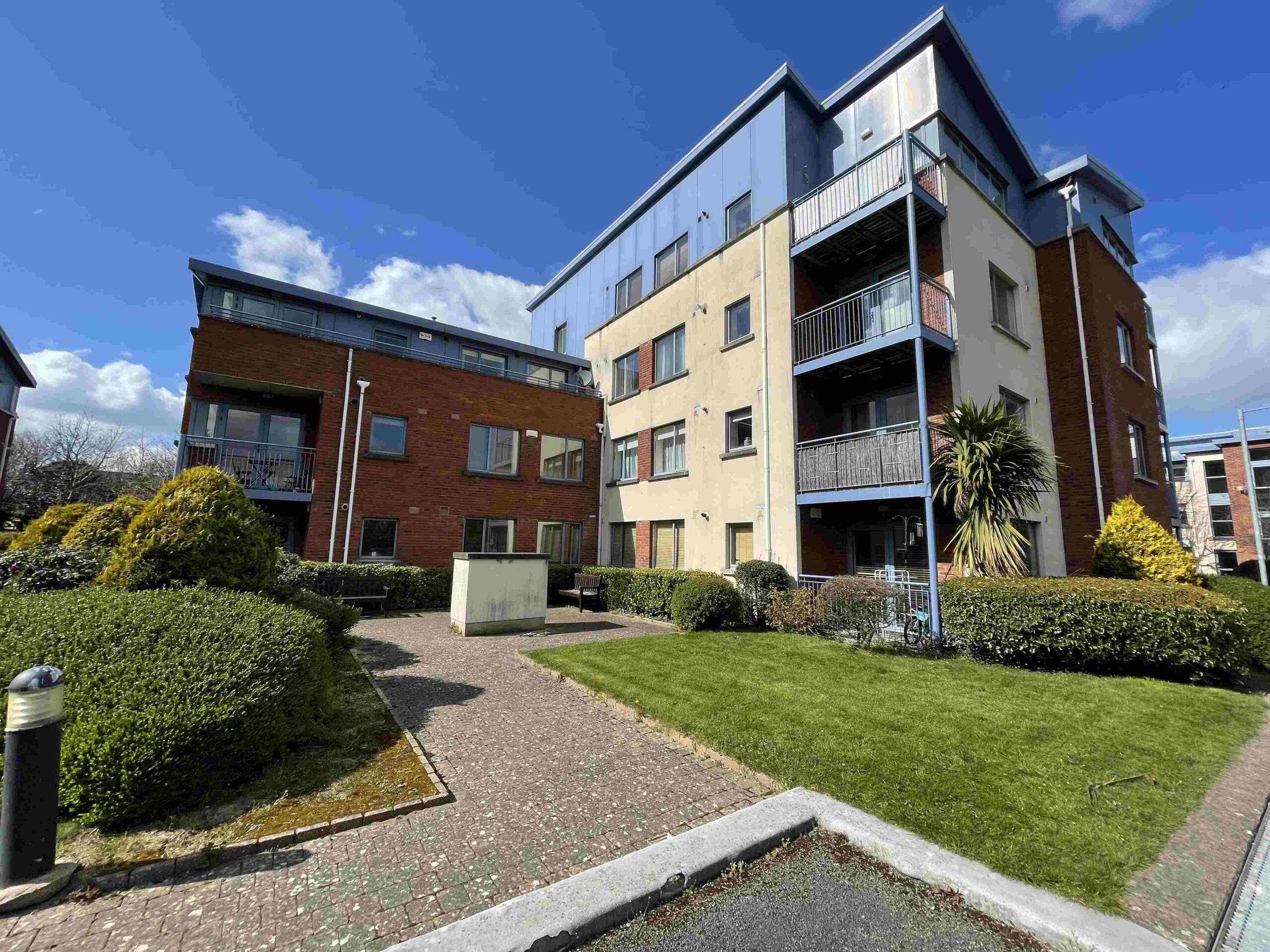 An apartment building with bushes in front of it, offering Expert Removals services.