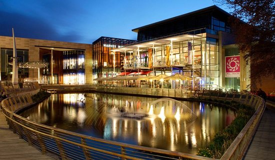 A building with a tranquil pond in front of it at night.