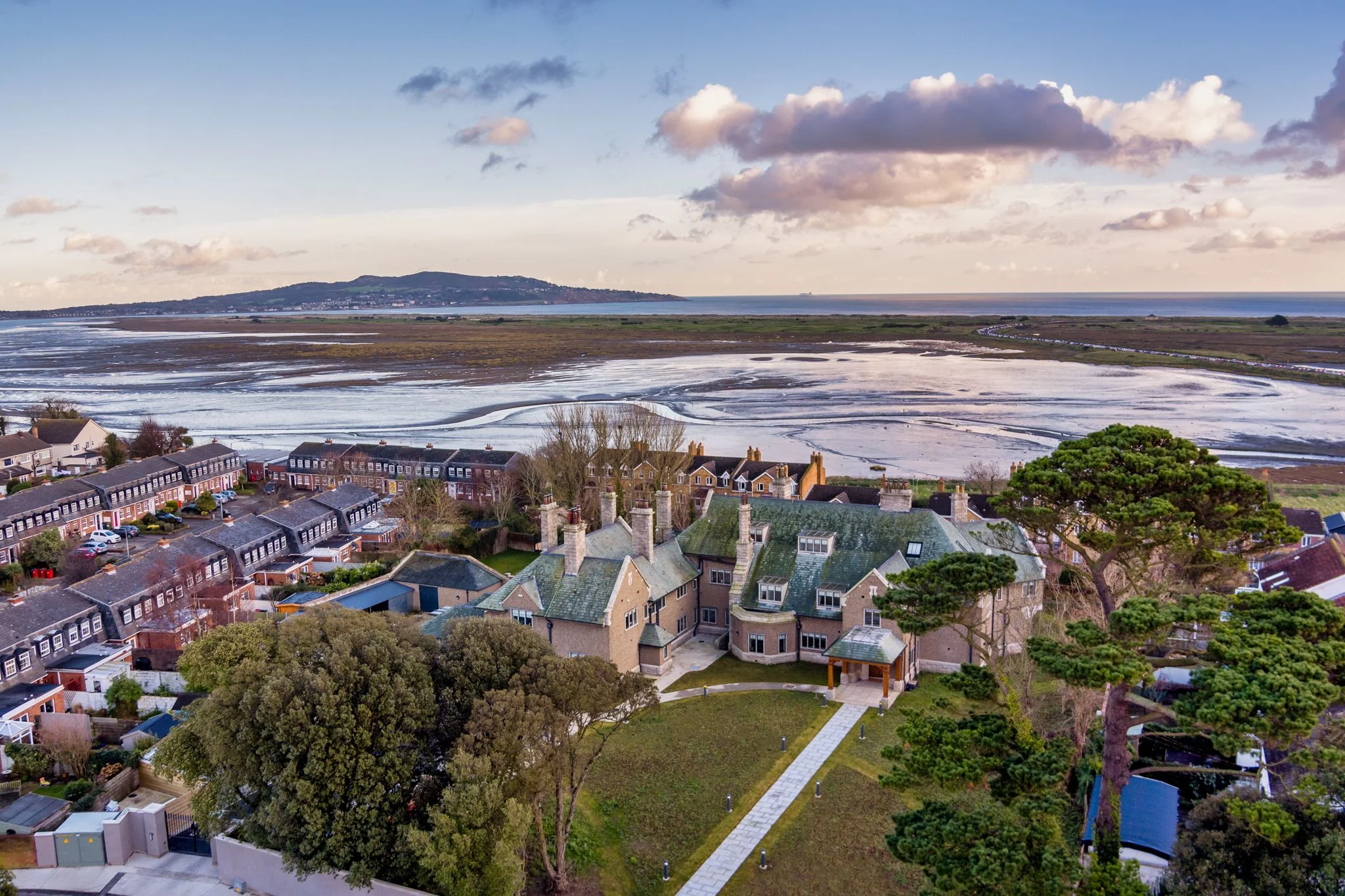 An aerial view of a house situated near the water, offering Expert Removals service.